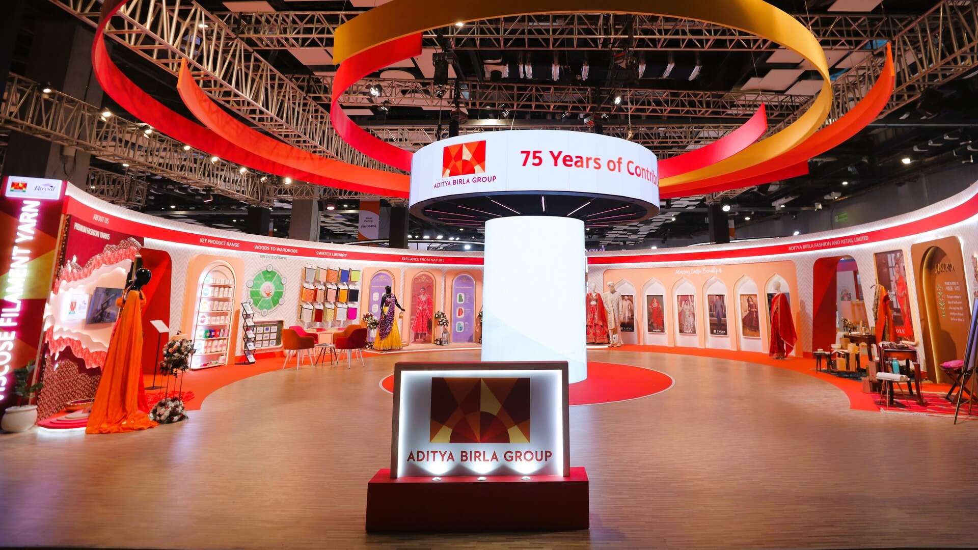 A striking showcase of various clothing pieces arranged for visual impact with a lighted sign in front that says Aditya Birla Group.