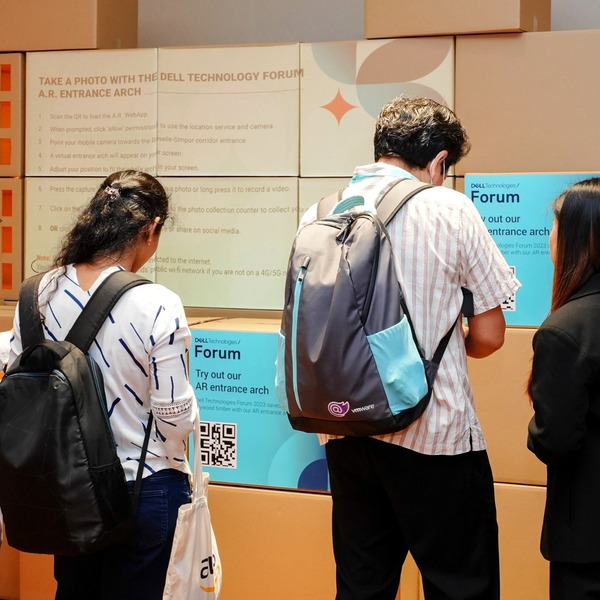 Dell Technologies Forum attendees scanning QR codes on cardboard boxes with text on them.