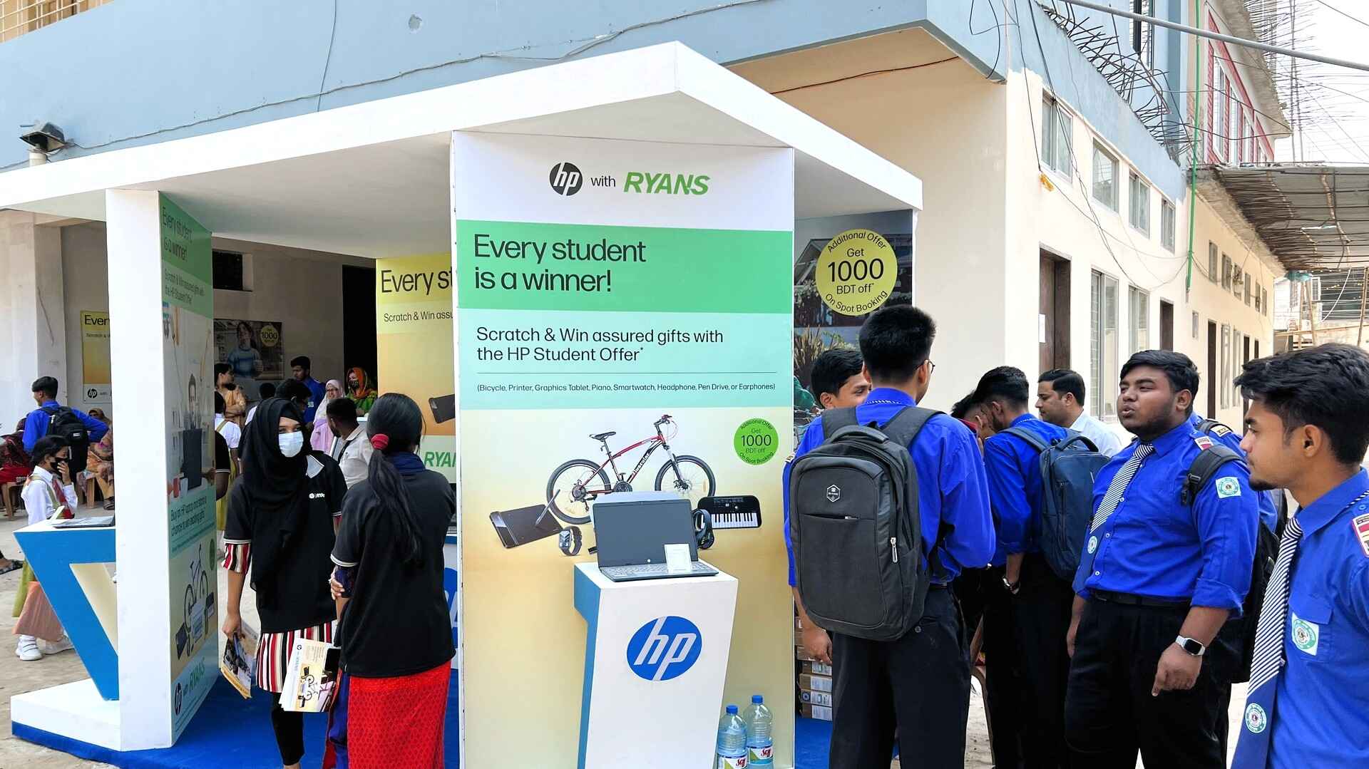 Students in blue uniforms gathering at the HP x Ryans Computers event booth, featuring HP laptops.