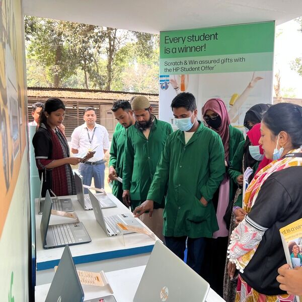 Students in green uniforms gathering at the HP x Ryans Computers event booth, exploring the HP laptops.