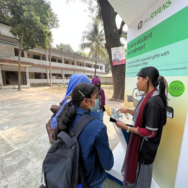 Female students gathering at the HP x Ryans Computers event booth, listening to a promoter.