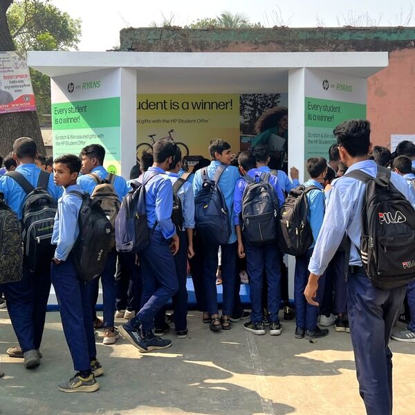 Students in blue uniforms exploring the HP x Ryans Computers event booth.