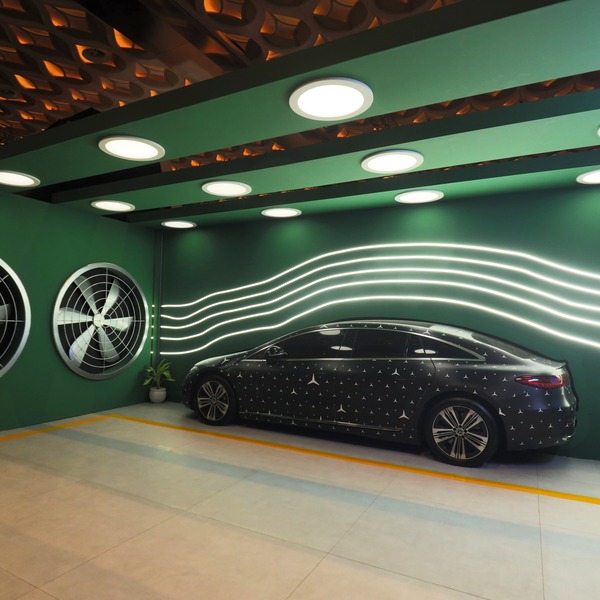 A parked Mercedes-Benz EQS against a striking green wall.