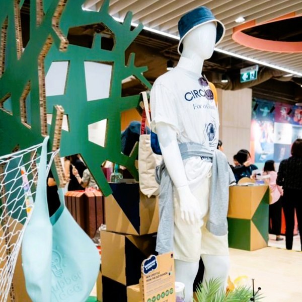 PMG-Thailand-Innovation-Day-2024-4.jpg A mannequin in eco-friendly apparel with a hat and a bag stands in front of a retail display.
